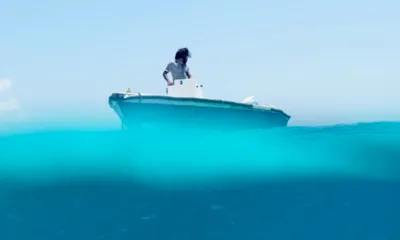 Misraab: Man standing at the console of a small motor boat seen from water level