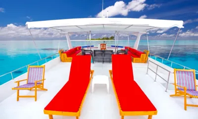Misraab: Top deck with red sun loungers, deck chairs and shaded seating facing a lagoon