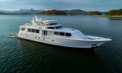 My Lady Alaska: Iate branco ancorado em uma baía calma com colinas florestadas e picos nevados ao fundo