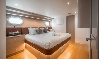 Sea Bear: Cabine dupla com cama branca, toalhas enroladas, vigias e piso de madeira