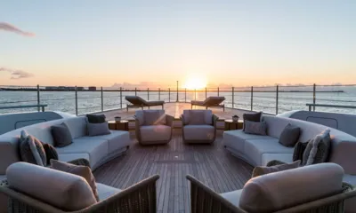 Caltex: Lounge no convés de proa com sofás curvos e poltronas voltados para espreguiçadeiras e um pôr do sol