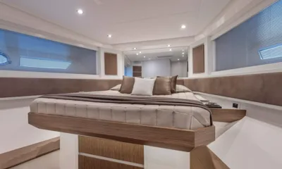 Spectre I: Cabina con letto matrimoniale centrale, copriletto trapuntato beige, cuscini, ampie finestre e specchio