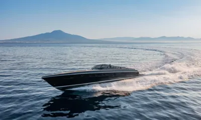 Spectre I: Yacht a motore nero che naviga veloce su acqua calma con montagna sullo sfondo e scia curva