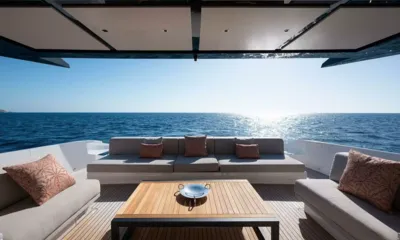 Spare Wheels: Shaded aft deck lounge with sofas and teak table facing open sea