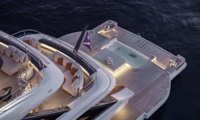 Cada Dia: High view of lit aft deck with pool, sunpad and curved lounge at dusk