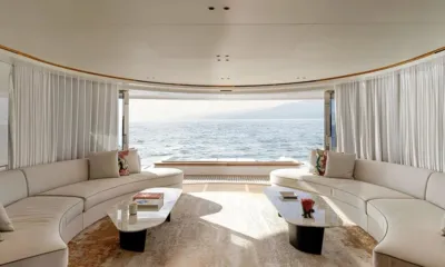 Cada Dia: Bright saloon with curved white sofas and marble tables opening to the sea