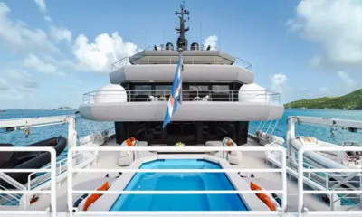 Q: Vista para a proa sobre uma piscina no convés até a superestrutura escalonada, com botes auxiliares de ambos os lados