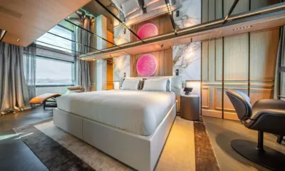 Raja 2: Cabine com cama de casal branca, obras de arte redondas rosa, poltrona e janelas altas