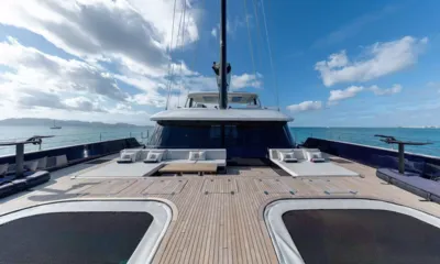 Belldia: Ponte di prua in teak con reti trampolino, sedute lounge e albero contro il cielo blu