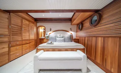 Surfbird: Cabine com painéis de madeira, cama de casal, banco estofado, armários e vigias
