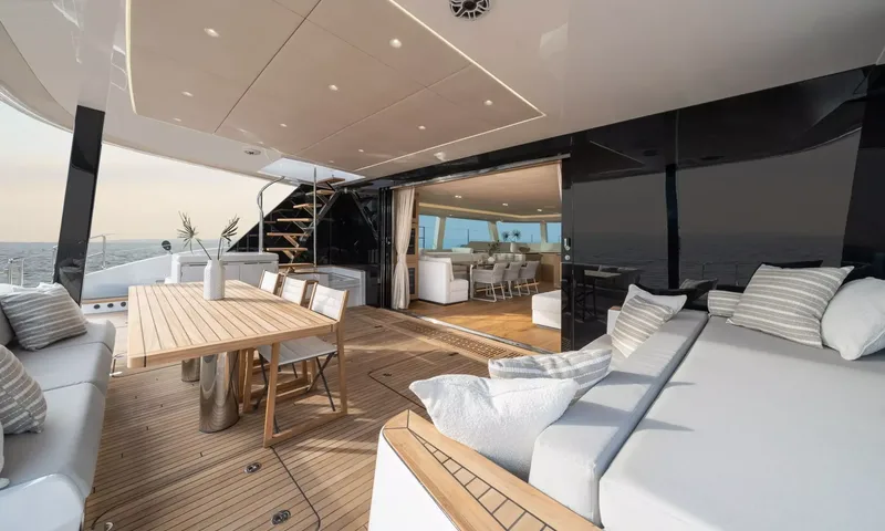 Ankawer VI: Covered aft deck with cushioned sofas, teak dining table and open doors to saloon