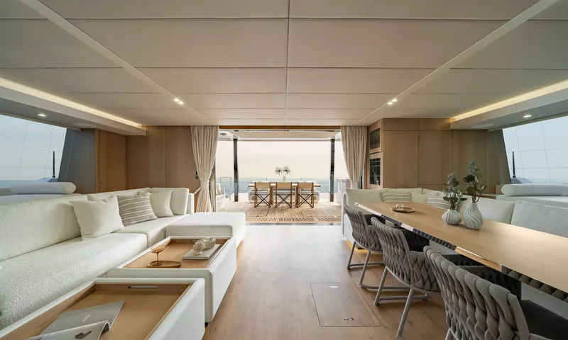 Ankawer VI: Bright saloon with white sofa, long dining table and view through to aft deck