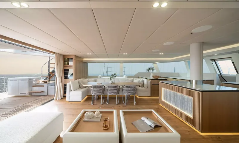 Ankawer VI: Open saloon with dining area, ottomans, lit island counter and doors to aft deck