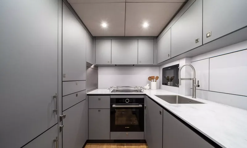 Ankawer VI: Grey galley with oven, cooktop, steel sink and white countertops