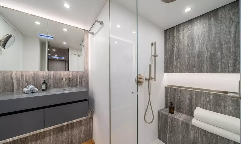Ankawer VI: Bathroom with grey stone walls, vanity sink, mirror and glass walk in shower