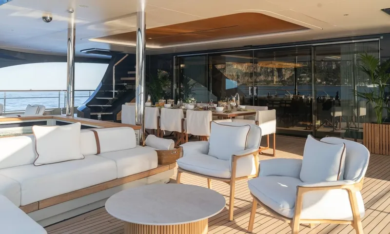 Seawolf X: Covered deck with armchairs, sofa and a dining table by glass doors