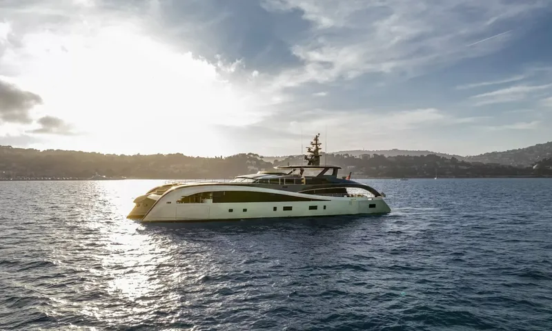 Seawolf X: Catamaran yacht in profile on sparkling water with wooded hills and a bright sky behind