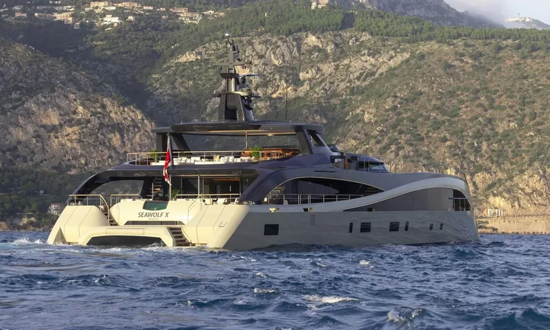 Seawolf X: Stern view of the yacht with twin hulls and stairs, mountains behind