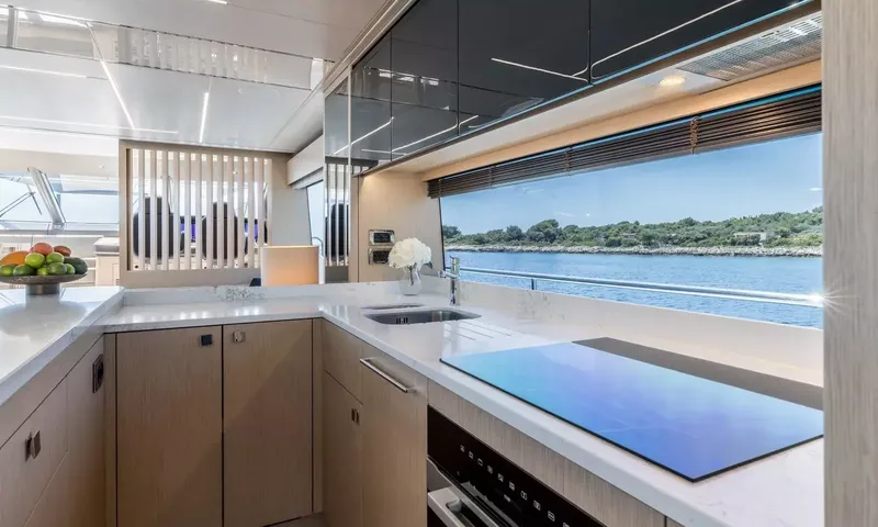 Ascend: Galley with white counters, sink, induction hob and a window onto the sea