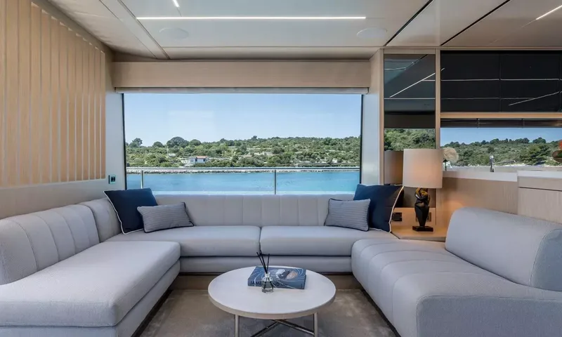 Ascend: Light grey sofa arrangement facing a wide window with a view of the coast