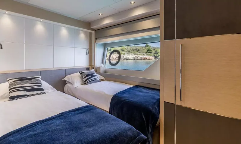 Ascend: Twin cabin with two single beds, navy throws and a sea view window