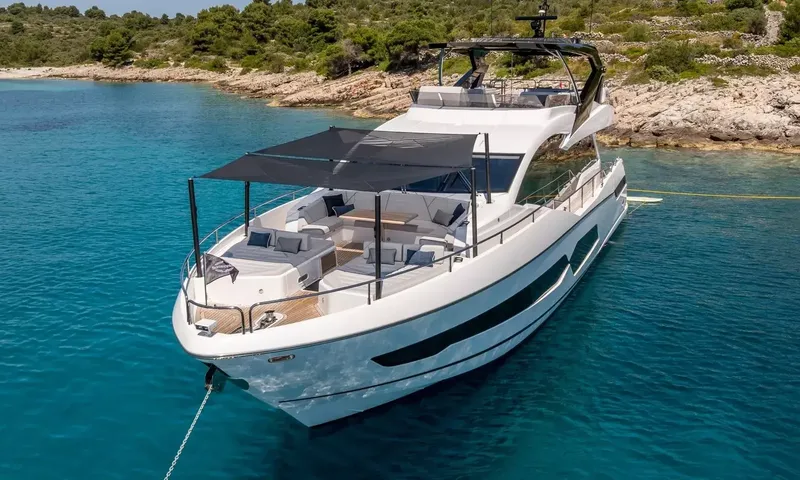 Ascend: Raised bow view of the yacht at anchor with shaded foredeck sunpads and seating
