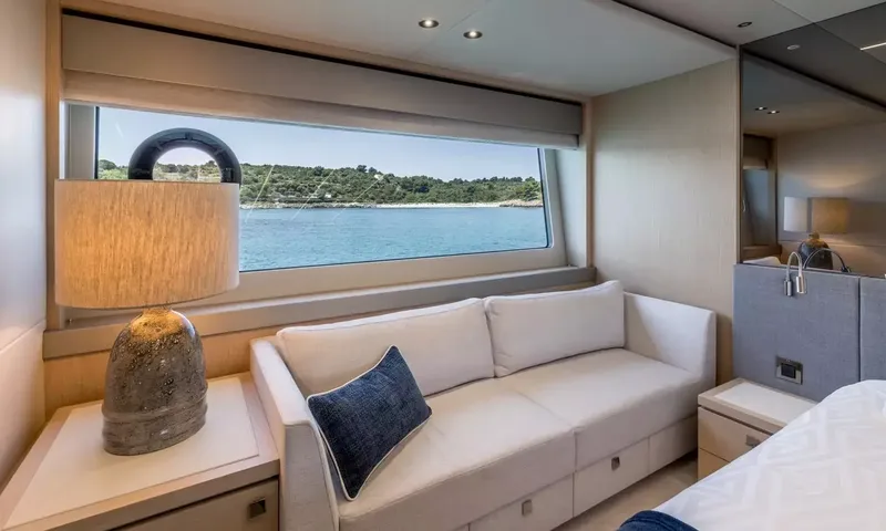 Ascend: Cabin corner with white sofa, table lamp and window looking out to the bay