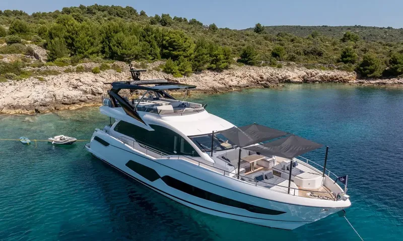 Ascend: Elevated view of the yacht at anchor with shaded foredeck lounge and a small tender nearby