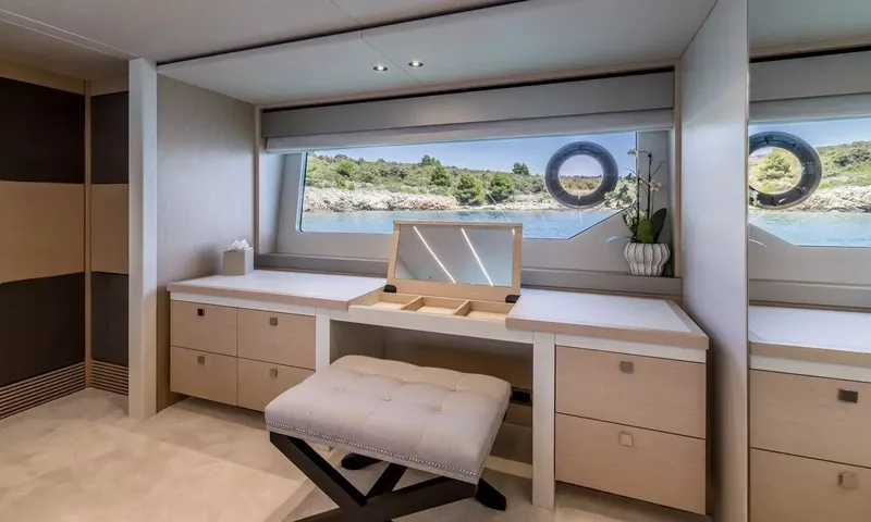 Ascend: Cabin vanity desk with flip up mirror, tufted stool and window view of a green shoreline