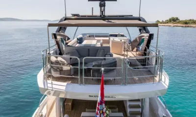 Ascend: Upper deck seen from astern with lounge chairs, sofas and a canopy above turquoise water