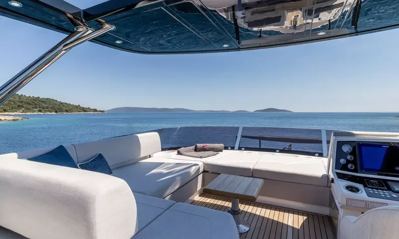 Ascend: Upper deck helm station beside L shaped seating and small table facing the open sea
