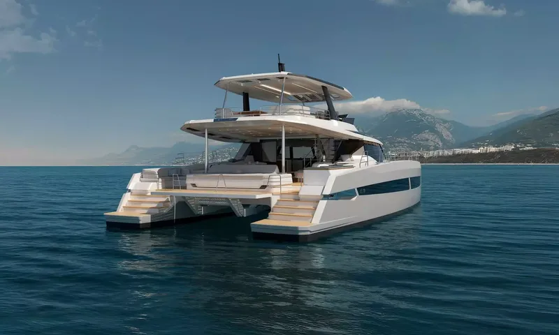 Elly II: Stern view of a catamaran with aft lounge, steps down both hulls and mountains behind