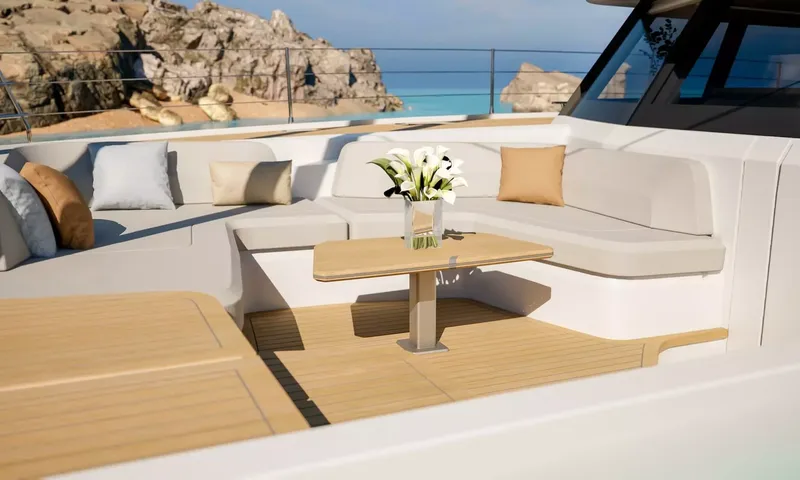 Elly II: Curved foredeck sofa with cushions and a table holding white flowers