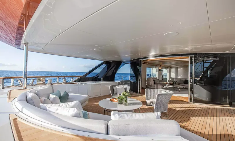 Angel: Covered aft deck with curved white sofa, round table and wicker chairs opening to the saloon