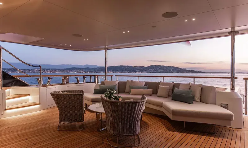 Angel: Covered deck lounge with sofa and wicker armchairs overlooking a coastline at dusk