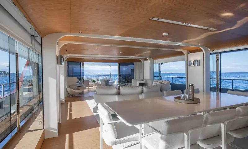 Angel: Indoor dining table with white chairs leading into a lounge with sea views