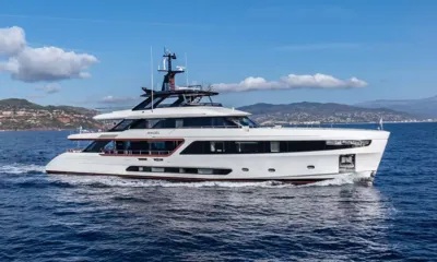 Angel: White motor yacht cruising on blue water with coastal hills behind