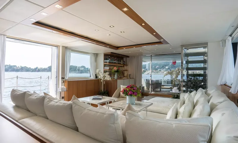 Kristo: Lounge with large cream sofa, glass coffee tables, flowers and wide windows onto the sea
