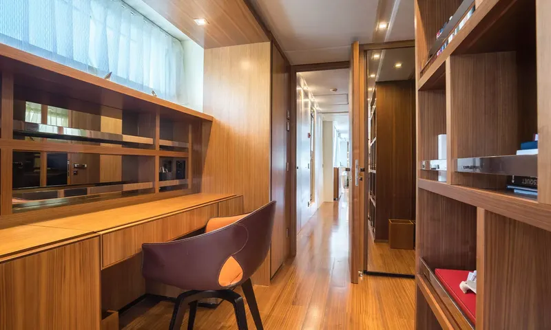 Kristo: Wood panelled study nook with desk and chair beside open shelving and a corridor