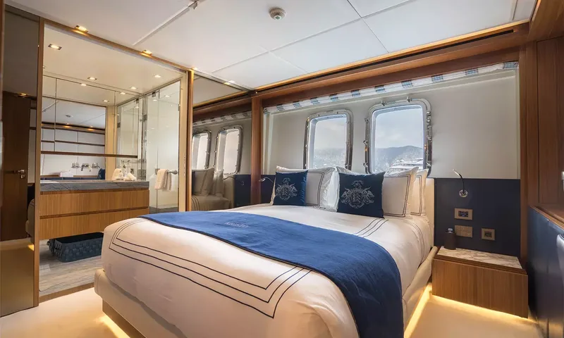 Kristo: Double cabin with navy throw, portholes and an open ensuite bathroom
