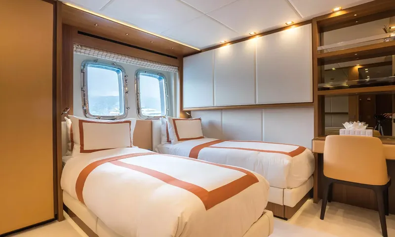 Kristo: Twin cabin with two single beds in orange trimmed linen, portholes and a desk