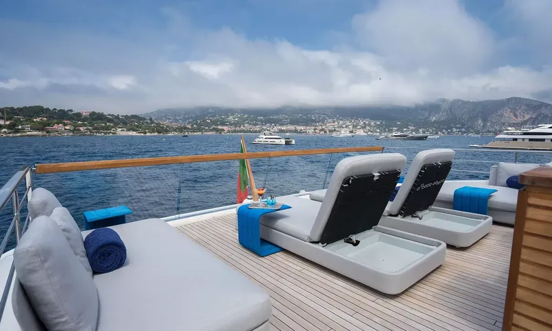 Kristo: Top deck sun loungers and daybed overlooking a bay with anchored boats and mountains