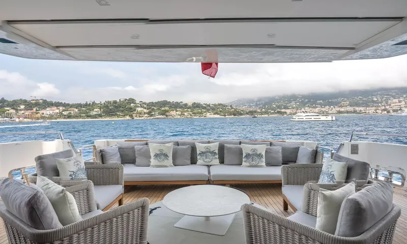 Kristo: Aft deck lounge with sofa, woven armchairs and round table facing the bay