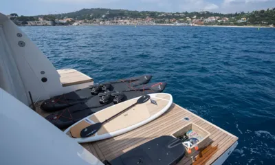 Kristo: Swim platform with underwater scooters, paddleboards, an electric foil board and snorkel gear facing a hillside town