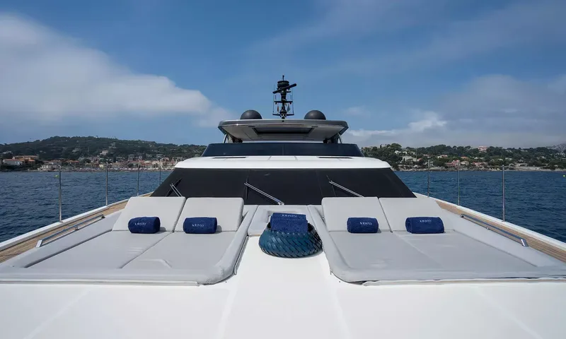 Kristo: Foredeck sunpads with blue towels in front of the superstructure, coastline behind