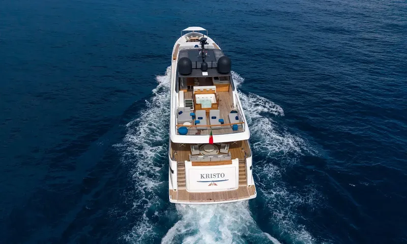 Kristo: Aerial stern view of the yacht under way leaving a white wake, jacuzzi on the upper deck