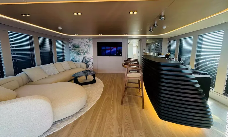 Oriy: Lounge com sofá curvo, piso de madeira e um bar escuro em camadas iluminado por baixo