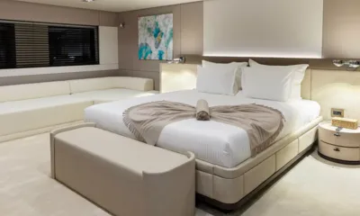 Oriy: Cabine com cama grande branca, manta dobrada, banco aos pés e sofá de canto