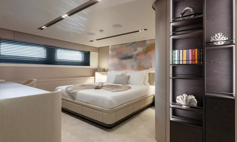 Oriy: Cabine com cama de casal sob uma obra de arte abstrata, persianas na janela e prateleiras com livros
