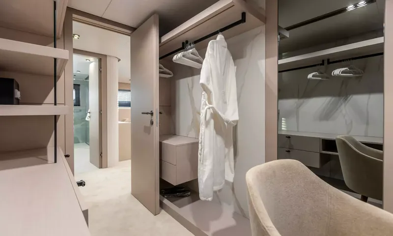 Oriy: Closet com um roupão branco em uma barra e porta aberta para um banheiro